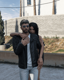 a man in a leather jacket is hugging a woman in sunglasses