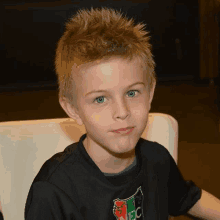 a young boy wearing a black shirt is sitting in a chair .