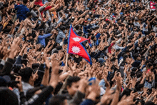 a crowd of people are raising their hands in the air while holding a nepal flag