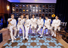 a group of men sitting in front of a wall of awards