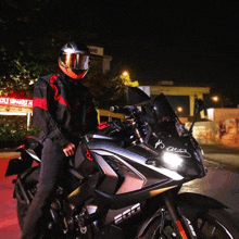 a man wearing a helmet and goggles stands next to a motorcycle with a sticker on the front that says atatürk