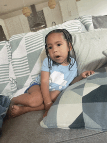 a baby is sitting on a couch wearing a blue shirt that says polar bear