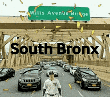 a man in a ny yankees jersey stands in the middle of a highway under a sign that says south bronx