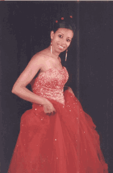 a woman in a red gown is smiling and holding her skirt