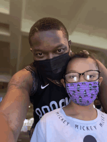 a man wearing a mickey mouse shirt and a girl wearing a purple mask