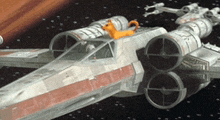 a model of a star wars x-wing fighter jet with a cat on top of it