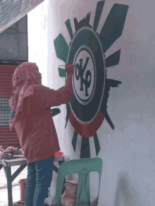 a woman is painting a circle with the letter o on it