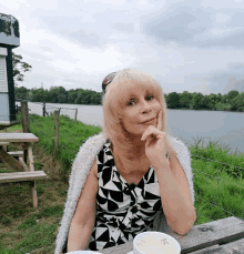 a woman in a black and white dress sits at a table with a bowl of soup