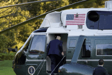 a man in a suit is getting out of a helicopter with an american flag on the side