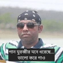 a man wearing a bandana , sunglasses and a green and white striped shirt .