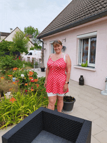 a woman in a red polka dot dress stands in front of a house