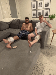 two men sitting on a couch with their feet wrapped in plastic