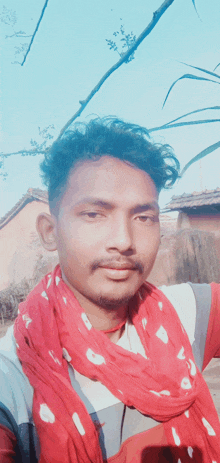 a man wearing a red scarf with white polka dots around his neck