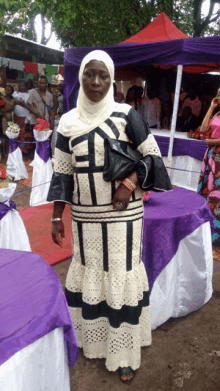 a woman in a black and white dress is standing in front of a table