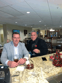 two men are sitting at a table with a bottle of wine