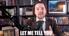 a man in a suit and tie is talking into a microphone and says " let me tell you "