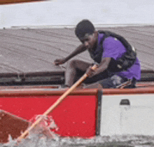 a man in a purple shirt is rowing a boat in the water