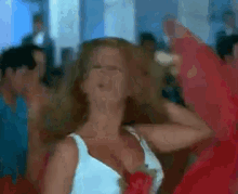 a woman in a white tank top is dancing in a crowd of people