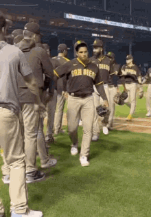 a group of baseball players are standing on a field . one of the players is wearing a san diego jersey .