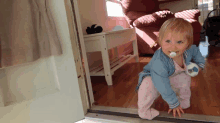 a baby with a pacifier in her mouth is crawling in a doorway