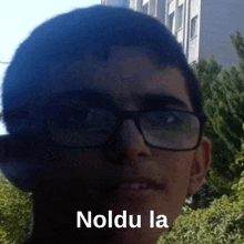 a young man wearing glasses has the word noldu la written on his face