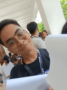 a man wearing glasses and a lanyard that says ' sydney ' on it smiles