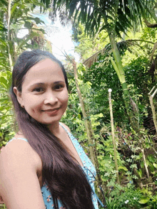 a woman with long hair is smiling in front of a forest