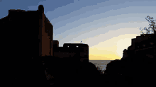 a silhouette of a building against a sunset sky