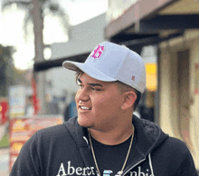 a man wearing a black hoodie and a white hat with a b on it