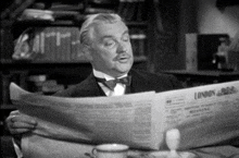 a man sitting at a table reading a newspaper that says london