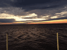 a sunset over a large body of water with a bridge in the distance