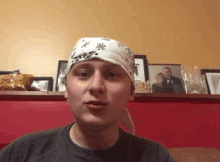 a man wearing a bandana with a picture of a man and woman behind him