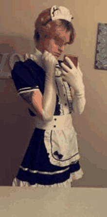 a young man in a maid costume is taking a selfie in front of a mirror .