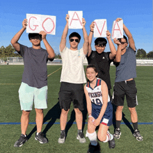 a girl in a vikings jersey holds up a sign that says go ava