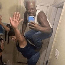 a man is sitting on a woman 's shoulders while taking a selfie in a bathroom .