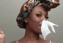 a woman wearing a head scarf is holding a napkin to her nose .