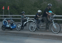 a man is riding a tandem bike with two children behind him