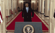 a man in a suit stands in front of a podium with the seal of the president of the united states