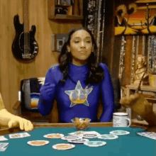 a woman in a blue superhero costume is sitting at a table with a bowl of chips and playing cards .