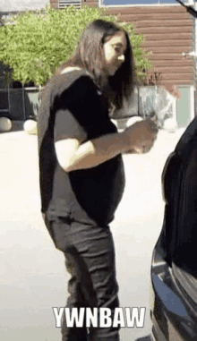 a woman is standing next to a car in a parking lot .