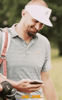 a man wearing a white hat and a striped shirt is looking at his phone