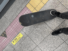 a person standing next to a skateboard with a yellow caution sign on the floor