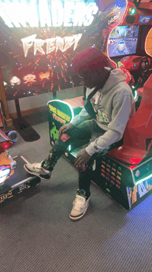 a man sits in front of an arcade machine that says invaders frenzy on it