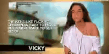 a woman in a white shirt is standing in front of a screen that says vicky