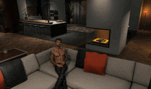 a shirtless man sits on a couch in a living room with a fireplace