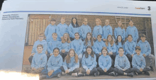 a group of children wearing blue sweatshirts are sitting on a newspaper page