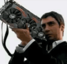 a man in a suit is holding a graphics card in his hands .