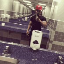 a man is taking a picture of himself in a public bathroom