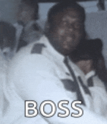 a man in a white shirt and tie is sitting in a car with the word boss written on the screen .