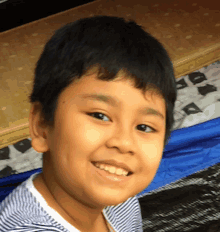 a young boy with a striped shirt is smiling for the camera